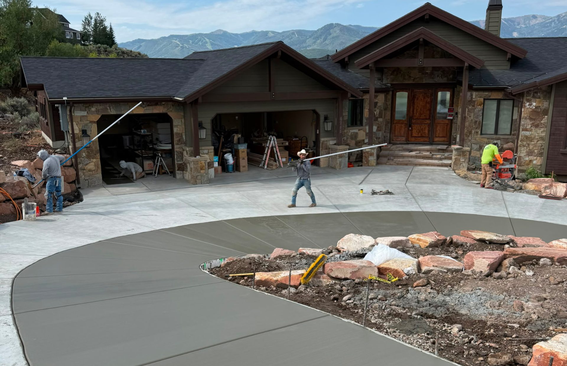 SetStone crew finishing a circular concrete driveway in front of a mountain home